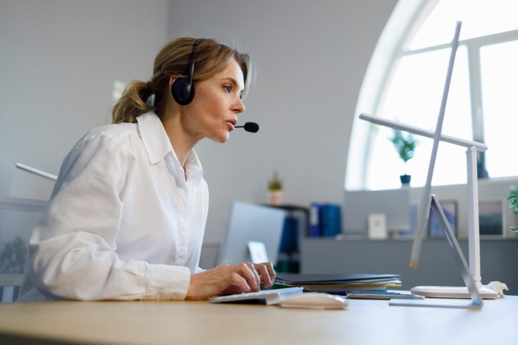 business woman helpline operator in headset working at computer