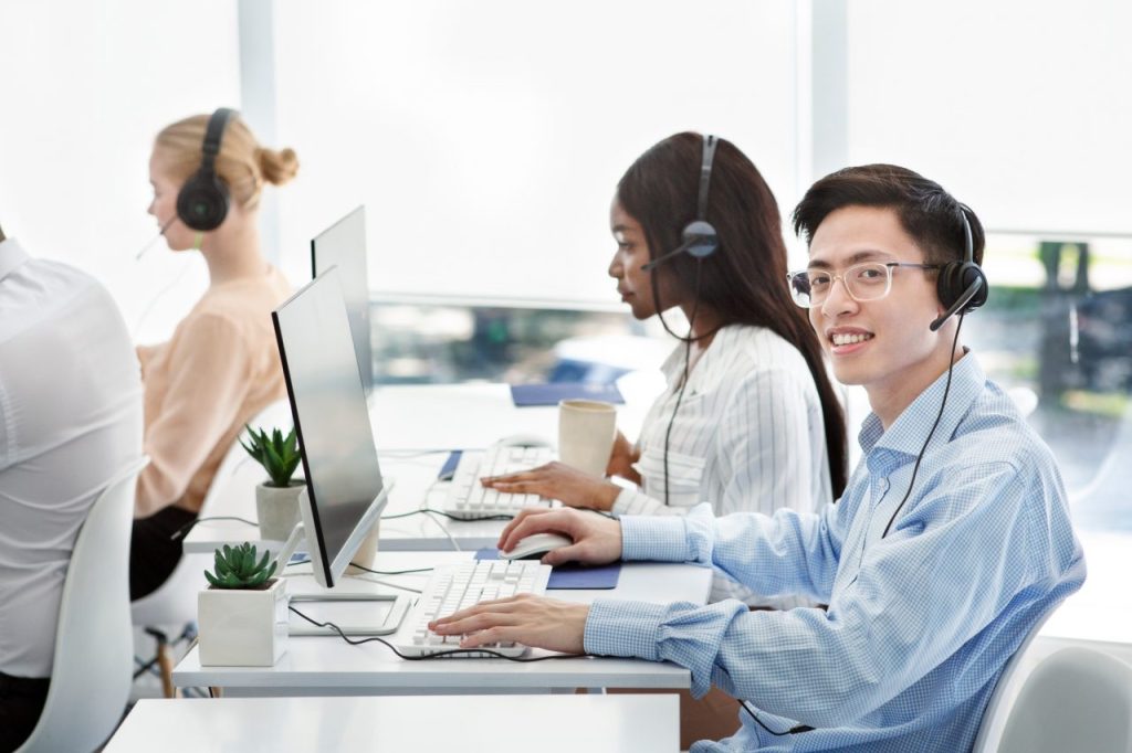 group of positive technical support managers working on hotline at call centre